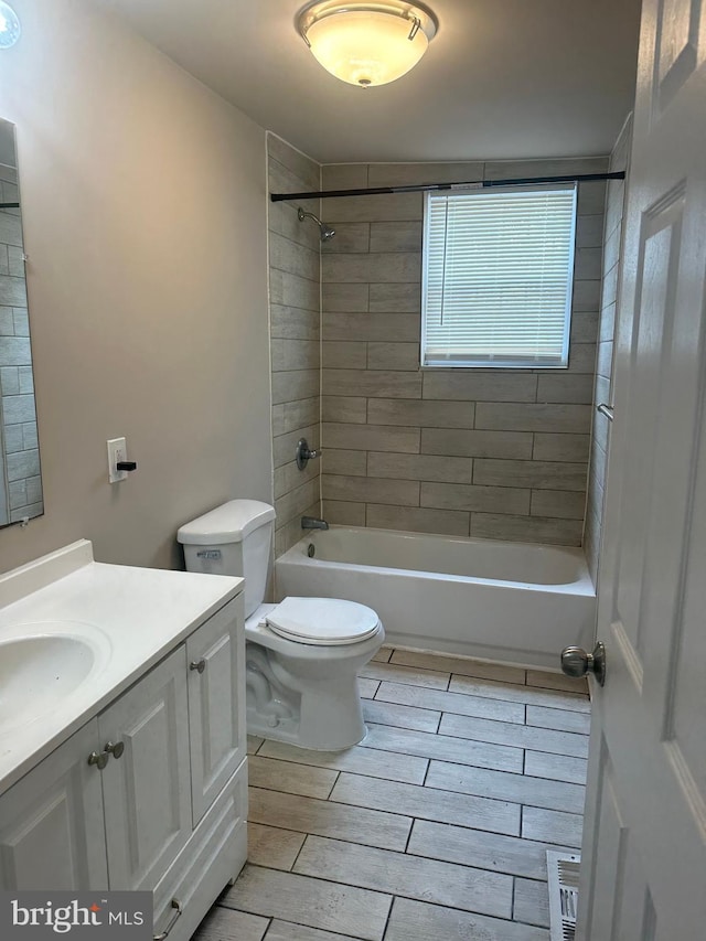 full bathroom with toilet, tiled shower / bath combo, and vanity