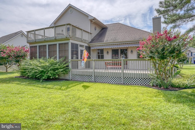 back of property featuring a sunroom, a wooden deck, and a lawn