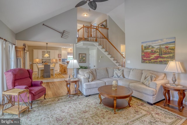 living room with light hardwood / wood-style flooring, high vaulted ceiling, and ceiling fan