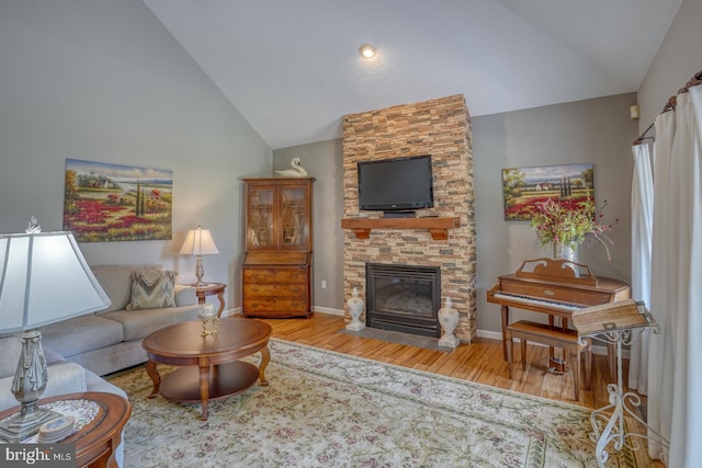 living room featuring high vaulted ceiling, a fireplace, and light wood-type flooring