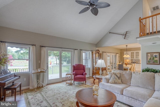 living room with ceiling fan, light hardwood / wood-style flooring, and high vaulted ceiling