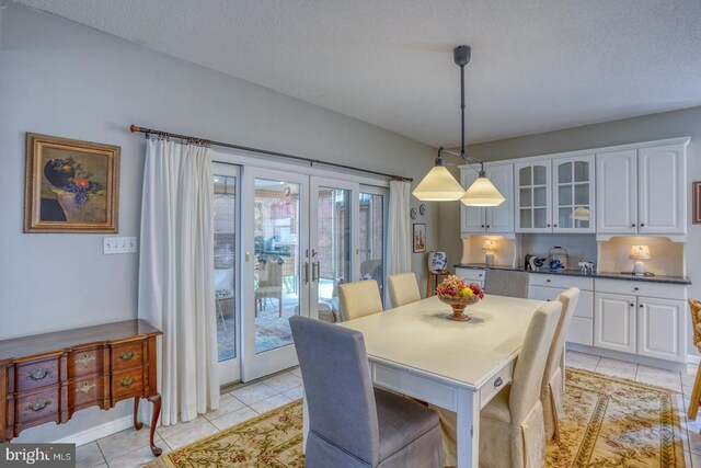 tiled dining room featuring french doors and a textured ceiling