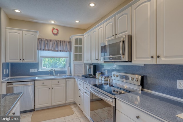 kitchen featuring appliances with stainless steel finishes, white cabinets, sink, backsplash, and light tile patterned floors