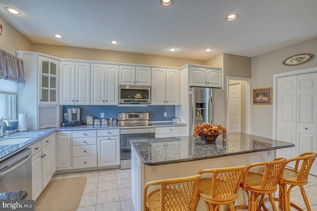 kitchen featuring light tile patterned flooring, decorative backsplash, white cabinets, sink, and appliances with stainless steel finishes