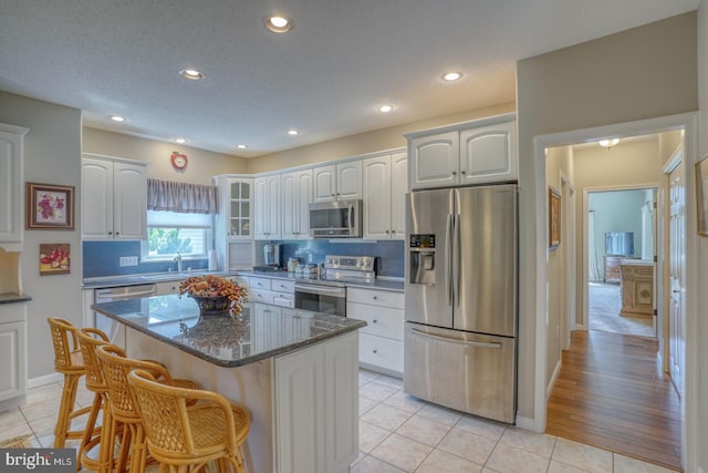 kitchen with appliances with stainless steel finishes, light tile patterned flooring, tasteful backsplash, and a kitchen island