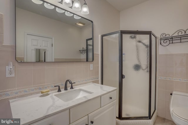 bathroom featuring vanity, an enclosed shower, tile walls, and toilet