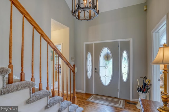 foyer entrance featuring a notable chandelier, hardwood / wood-style flooring, and high vaulted ceiling