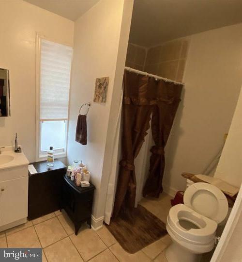 bathroom featuring curtained shower, tile patterned floors, vanity, and toilet