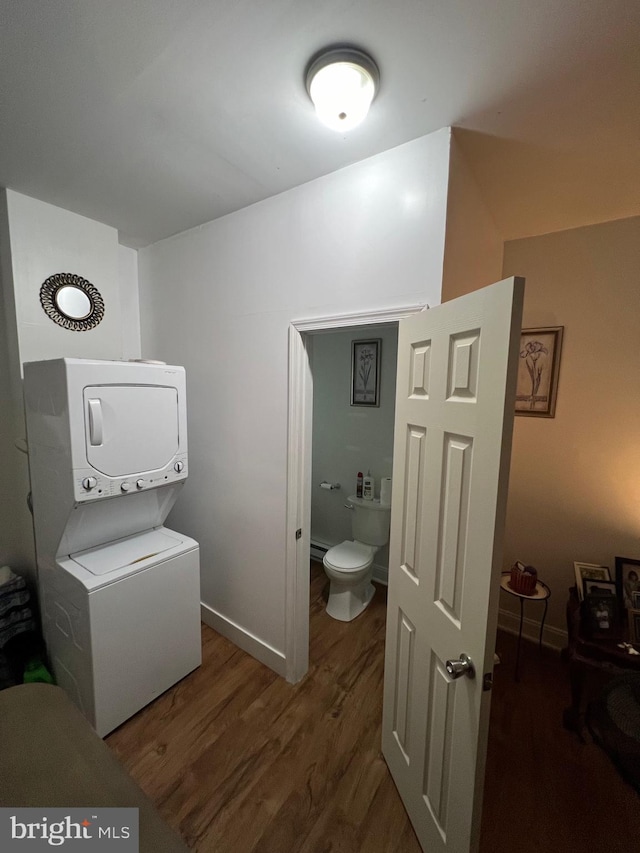 bathroom featuring wood-type flooring, stacked washer / drying machine, and toilet