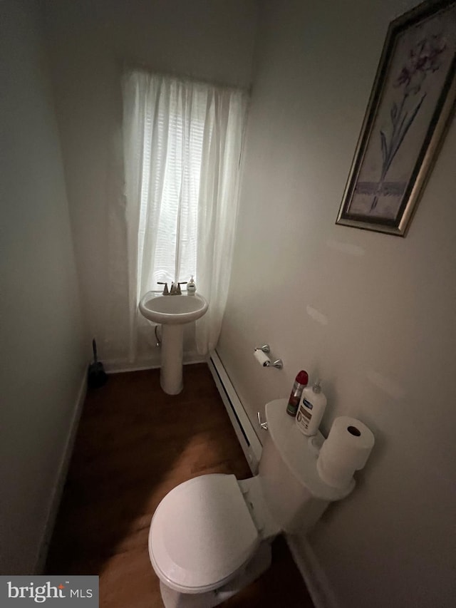 bathroom featuring toilet, baseboard heating, and hardwood / wood-style flooring