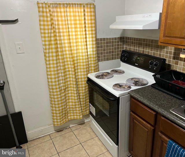 kitchen with light tile patterned floors, decorative backsplash, and electric range