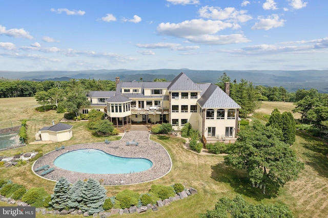 back of house with a balcony, a storage unit, and a swimming pool side deck