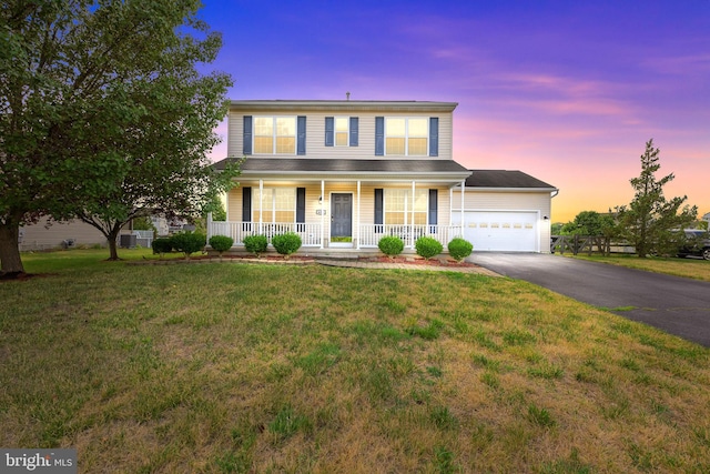 view of front of home featuring a lawn, covered porch, and a garage