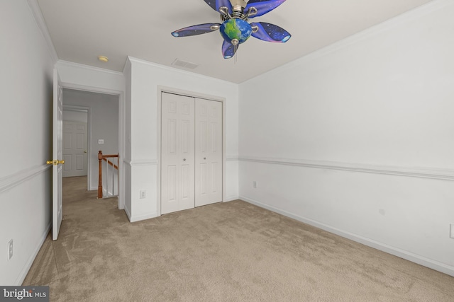 unfurnished bedroom featuring ceiling fan, light carpet, a closet, and ornamental molding