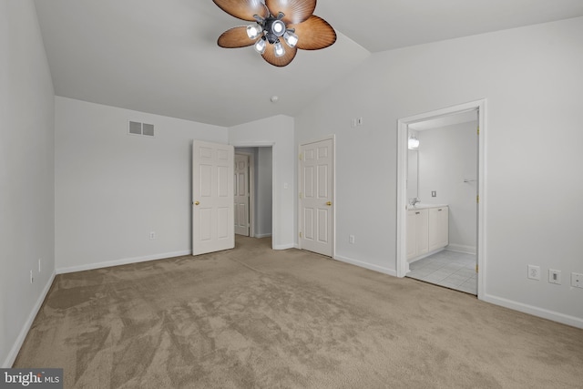 unfurnished bedroom featuring ceiling fan, light colored carpet, lofted ceiling, and ensuite bath