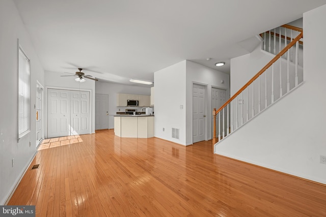 unfurnished living room featuring ceiling fan and light hardwood / wood-style floors