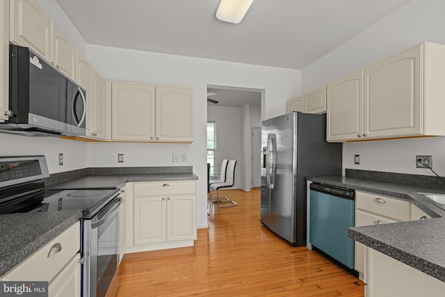 kitchen featuring stainless steel appliances, cream cabinetry, and light hardwood / wood-style flooring