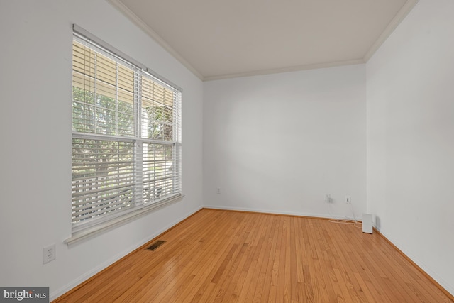 spare room featuring light wood-type flooring and crown molding