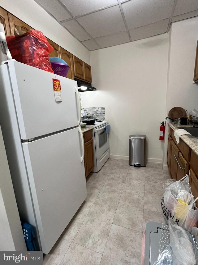 kitchen with a drop ceiling, light tile patterned floors, and white appliances