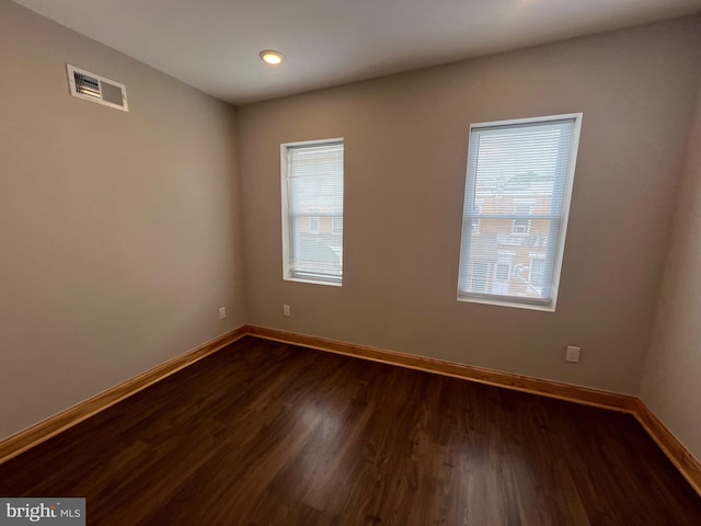 unfurnished room featuring dark wood-type flooring and a wealth of natural light