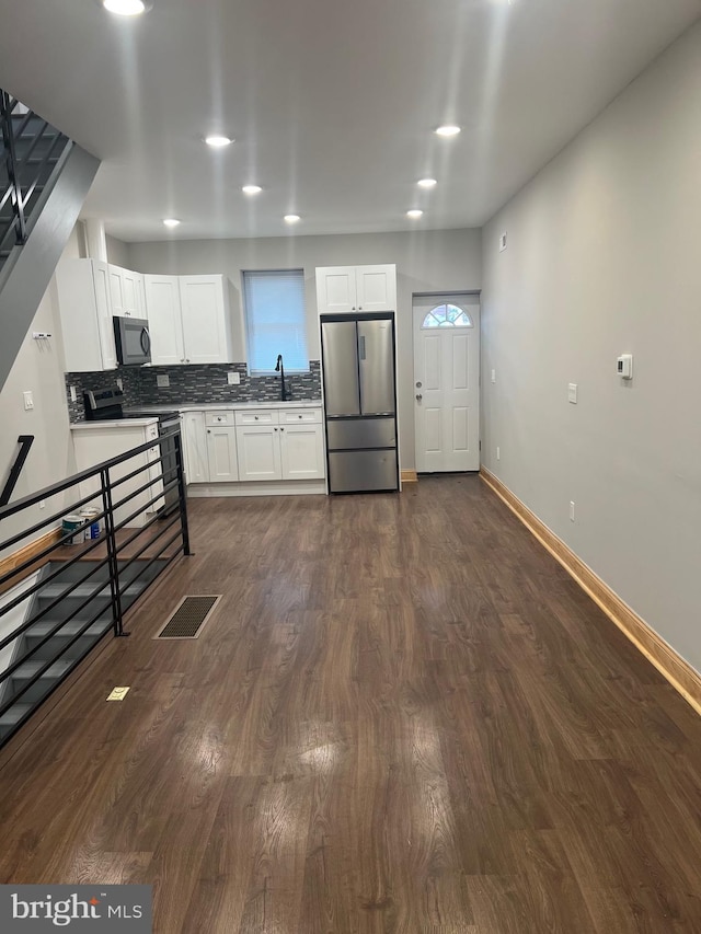 kitchen featuring dark hardwood / wood-style floors, decorative backsplash, sink, stainless steel appliances, and white cabinets