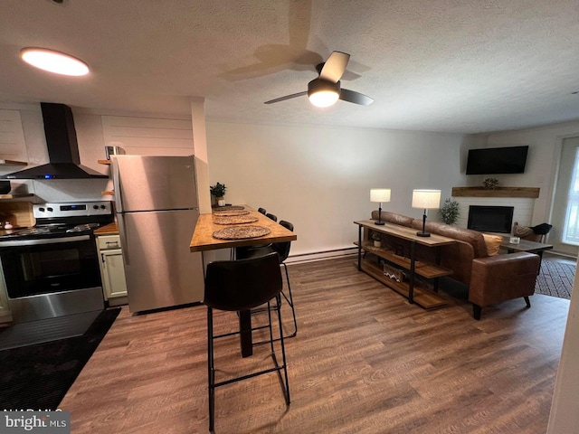 kitchen featuring extractor fan, wood-type flooring, stainless steel appliances, a textured ceiling, and white cabinets