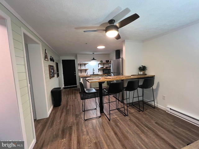 dining space with a baseboard radiator, a textured ceiling, and dark hardwood / wood-style flooring