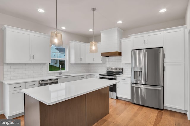 kitchen featuring light countertops, stainless steel appliances, premium range hood, white cabinetry, and a sink