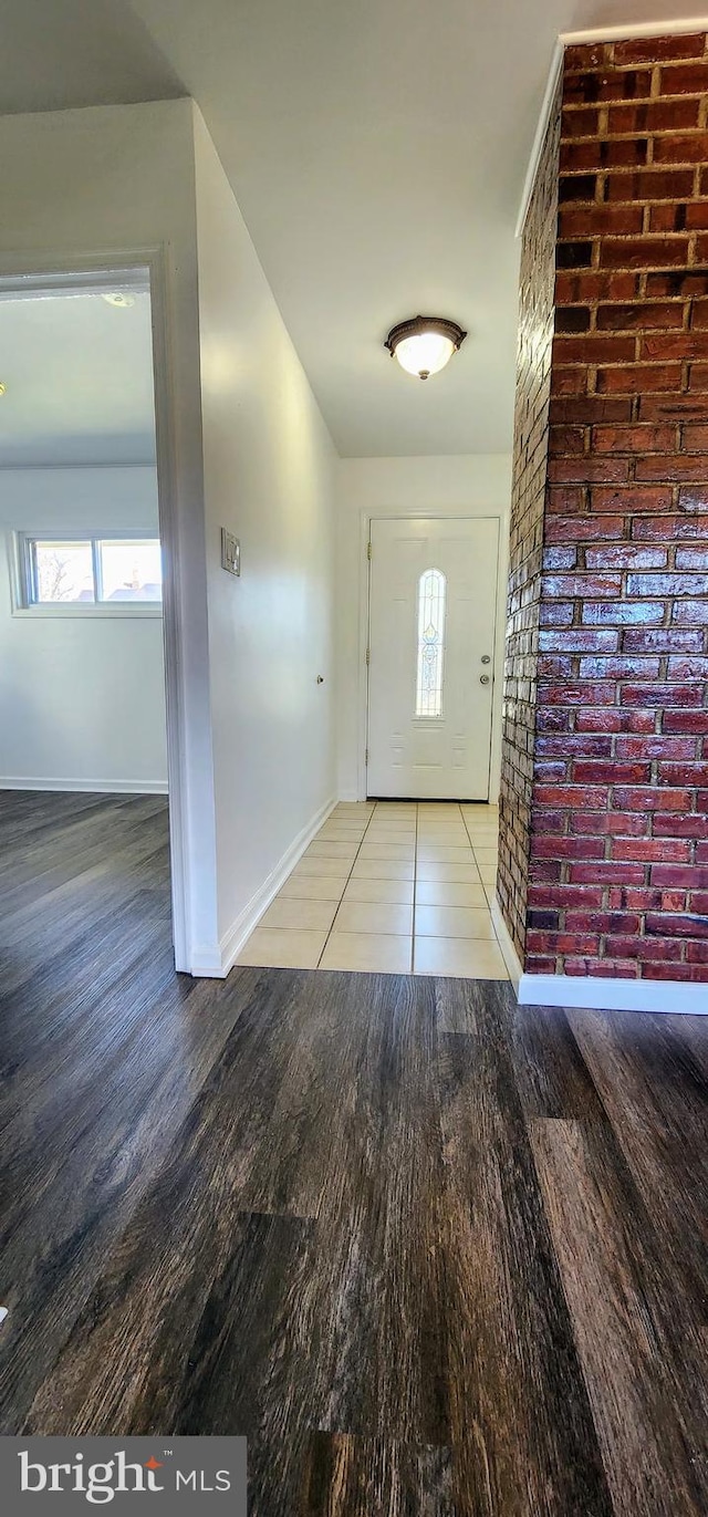 foyer entrance featuring brick wall and hardwood / wood-style flooring