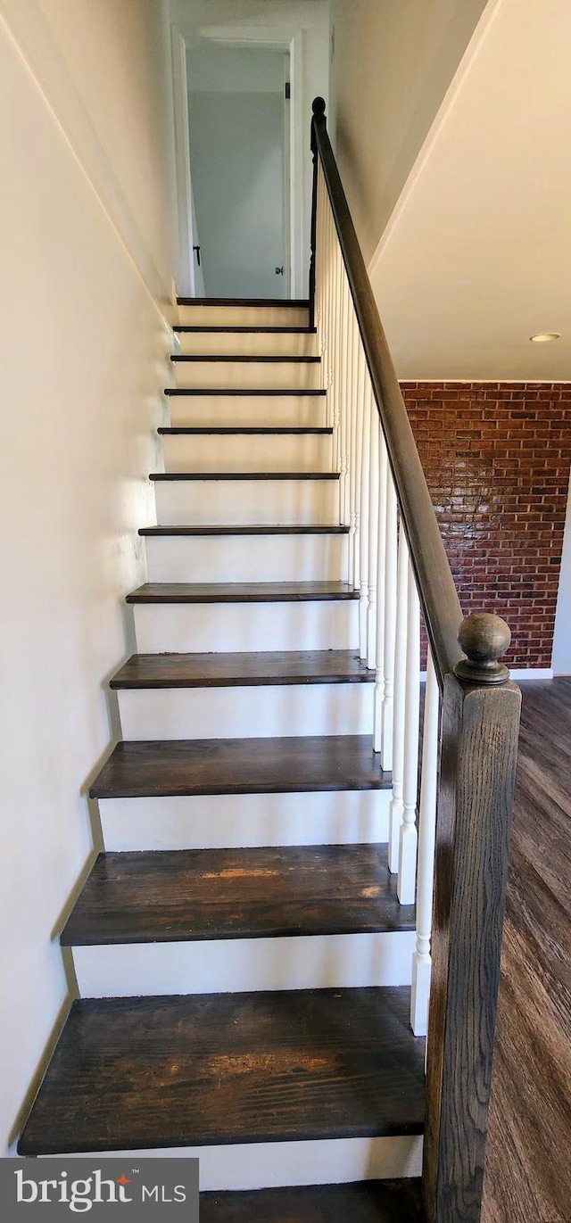 stairway featuring brick wall