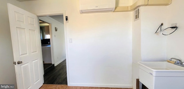 clothes washing area with wood-type flooring, an AC wall unit, and sink