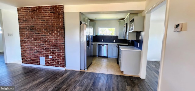 kitchen with sink, gray cabinetry, backsplash, stainless steel appliances, and hardwood / wood-style floors