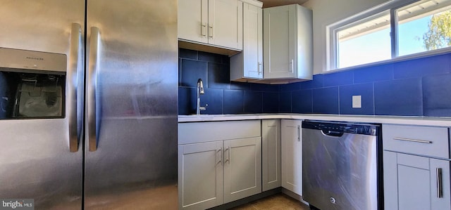 kitchen featuring stainless steel appliances, sink, decorative backsplash, and white cabinetry