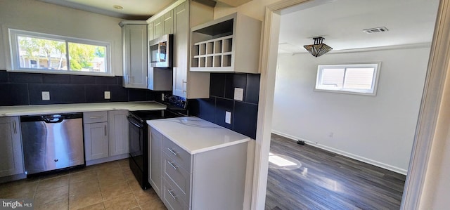 kitchen featuring gray cabinets, appliances with stainless steel finishes, decorative backsplash, and a healthy amount of sunlight