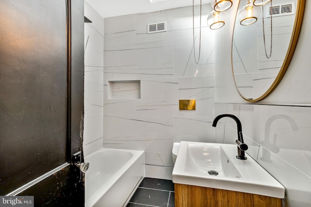 bathroom with vanity, tiled shower / bath combo, tile patterned flooring, and tile walls