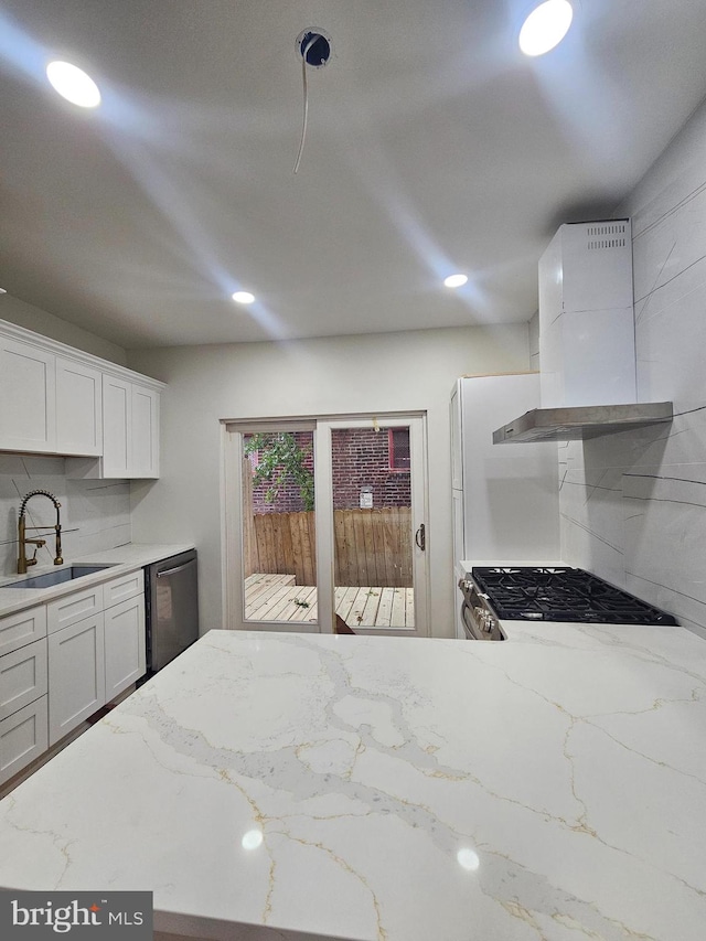 kitchen with backsplash, appliances with stainless steel finishes, white cabinetry, range hood, and sink