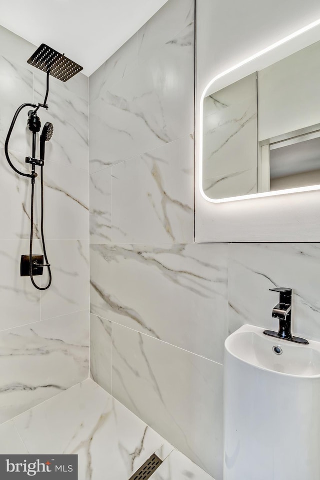 bathroom with a tile shower and sink