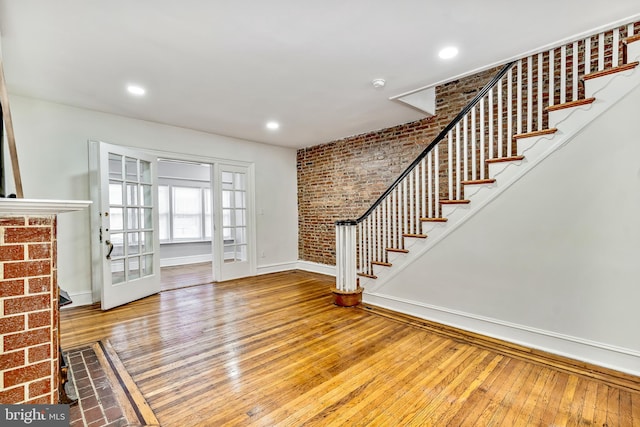 entryway featuring brick wall, french doors, and wood-type flooring