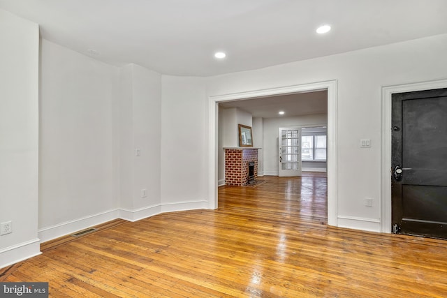 unfurnished room with light hardwood / wood-style flooring and a brick fireplace