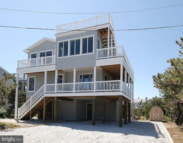 coastal inspired home with an outbuilding, a storage shed, driveway, stairway, and a carport