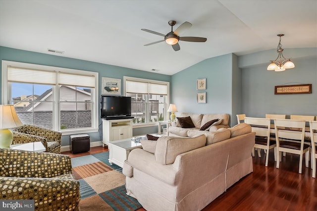 living area featuring dark wood-style flooring, visible vents, vaulted ceiling, baseboards, and ceiling fan with notable chandelier