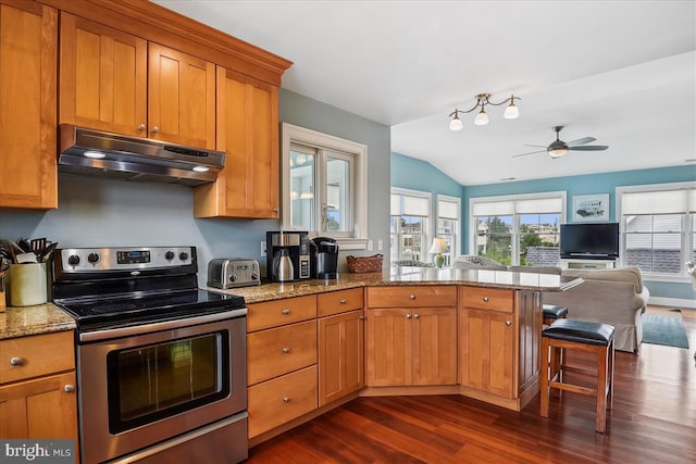 kitchen featuring stainless steel range with electric stovetop, light stone counters, under cabinet range hood, and a peninsula