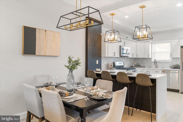 dining room featuring a raised ceiling, light hardwood / wood-style flooring, and sink