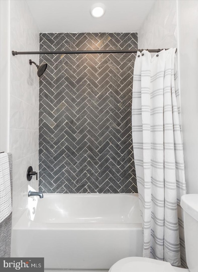 bathroom featuring shower / tub combo and toilet