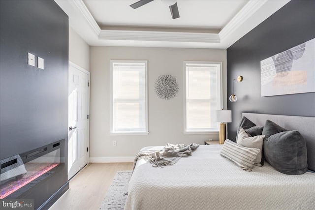 bedroom with ceiling fan, light hardwood / wood-style flooring, a raised ceiling, and ornamental molding