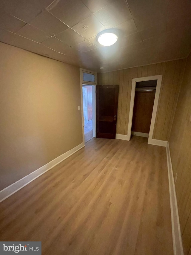 unfurnished room featuring hardwood / wood-style floors and wooden walls