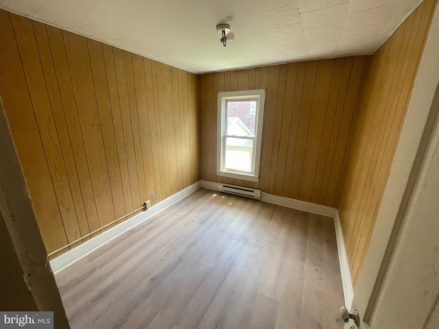 spare room with baseboard heating and wood walls