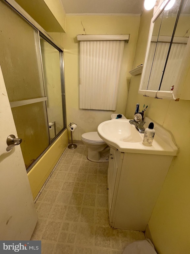 full bathroom with combined bath / shower with glass door, vanity, toilet, and crown molding