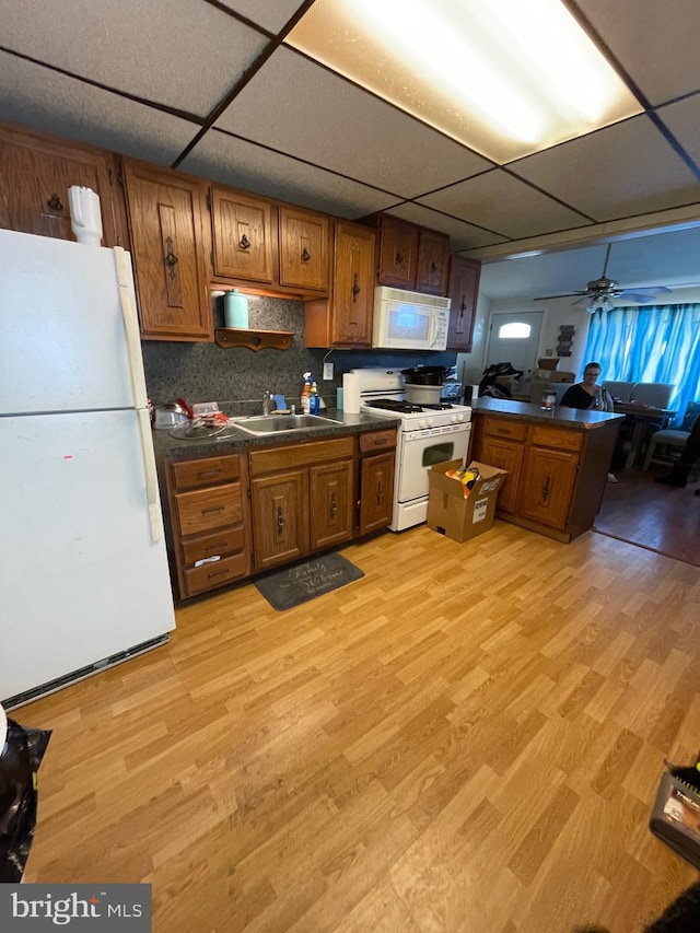 kitchen featuring light wood-type flooring, a paneled ceiling, white appliances, ceiling fan, and sink