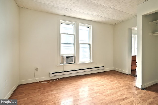 unfurnished room with cooling unit, baseboard heating, a drop ceiling, and light hardwood / wood-style flooring